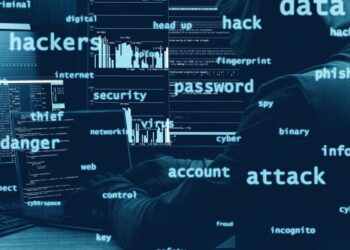 A person wearing a hoodie uses multiple computer screens in a dark room, with words like "hackers," "data," "password," and "attack" overlayed, suggesting cybercrime or a hacking attempt. | ZRYLY.com